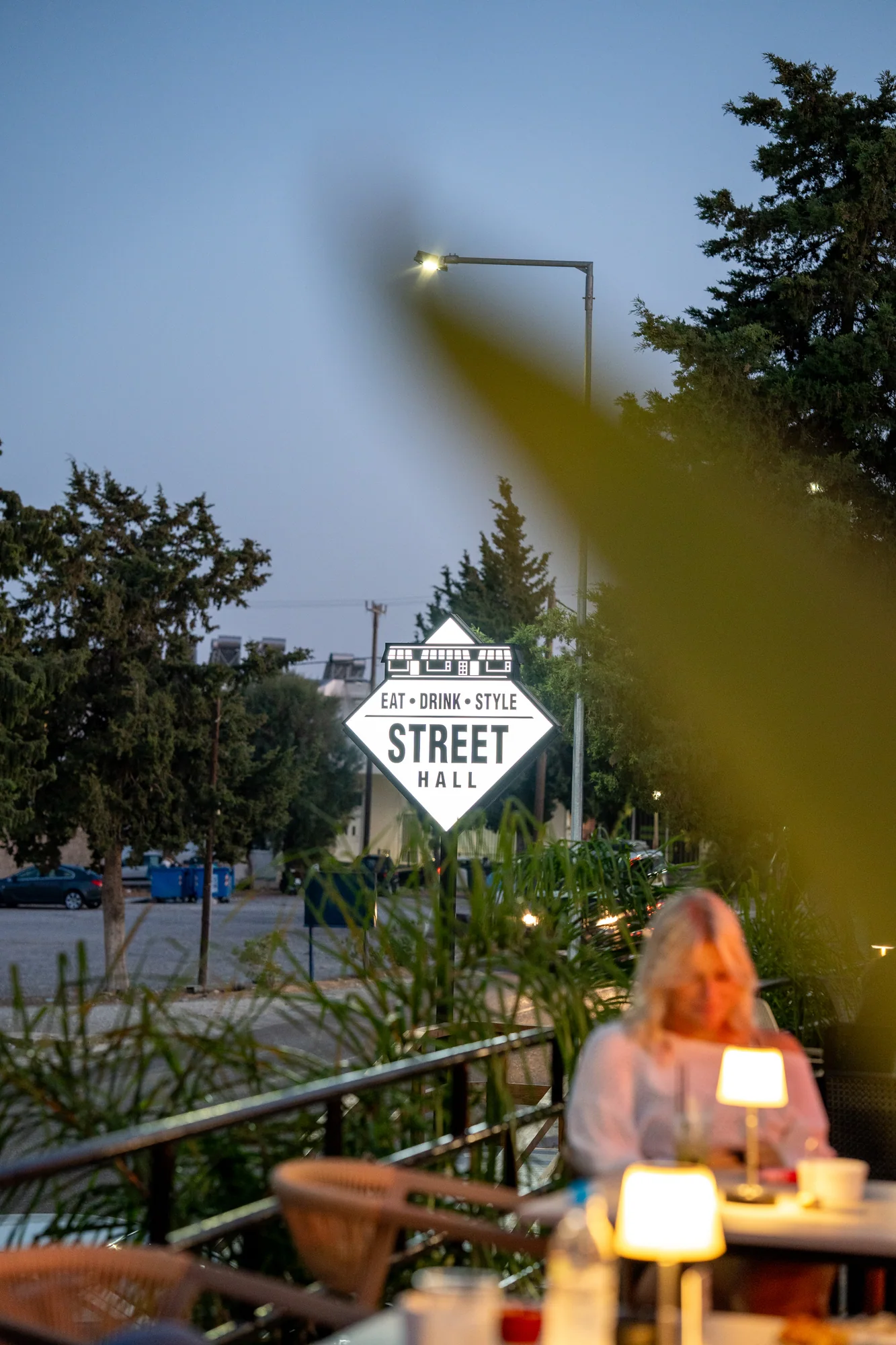 Evening terrace seating beside the Street Hall sign in Gennadi