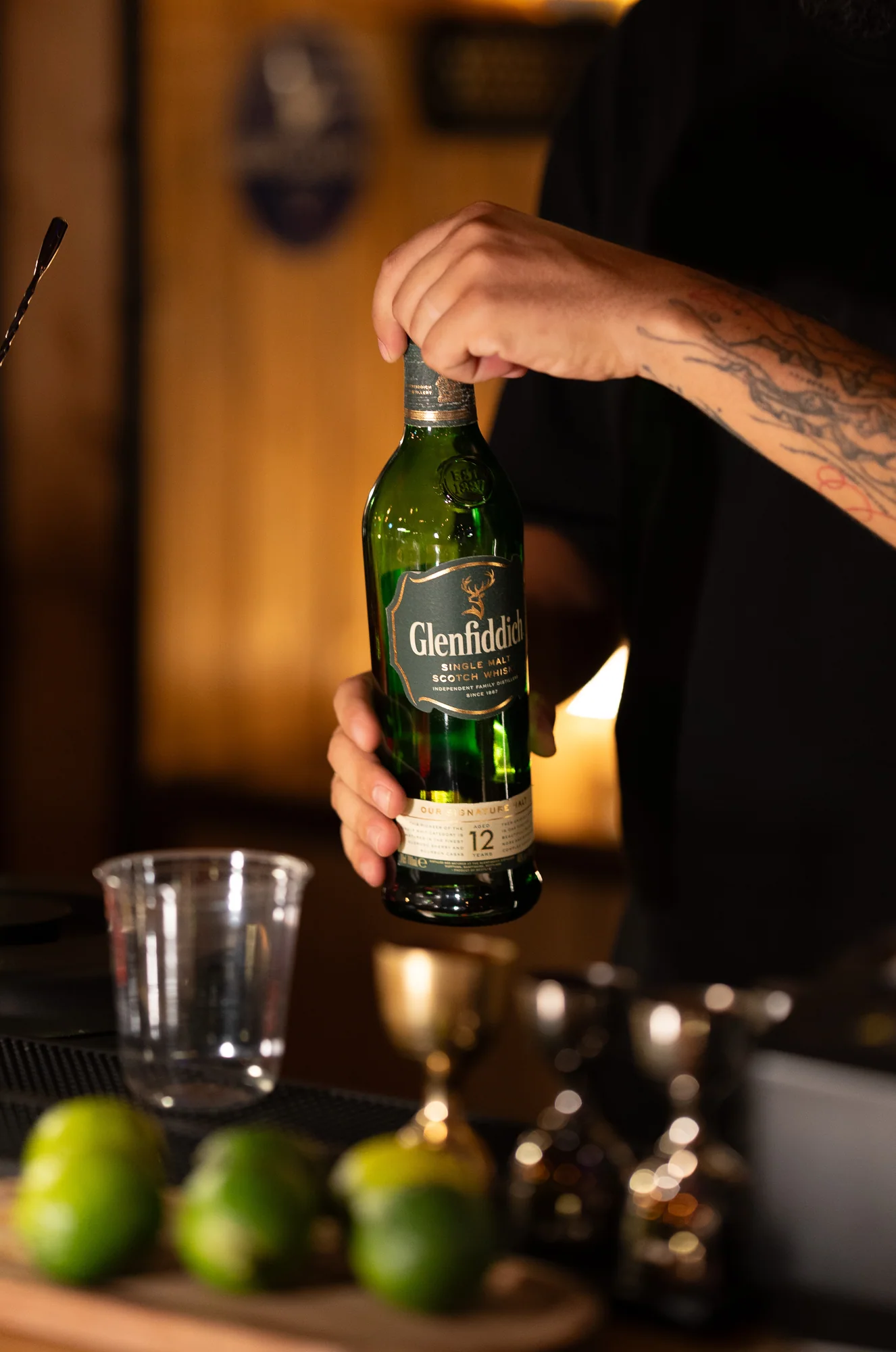 A bartender opening a bottle of Glenfiddich whisky at The Cup
