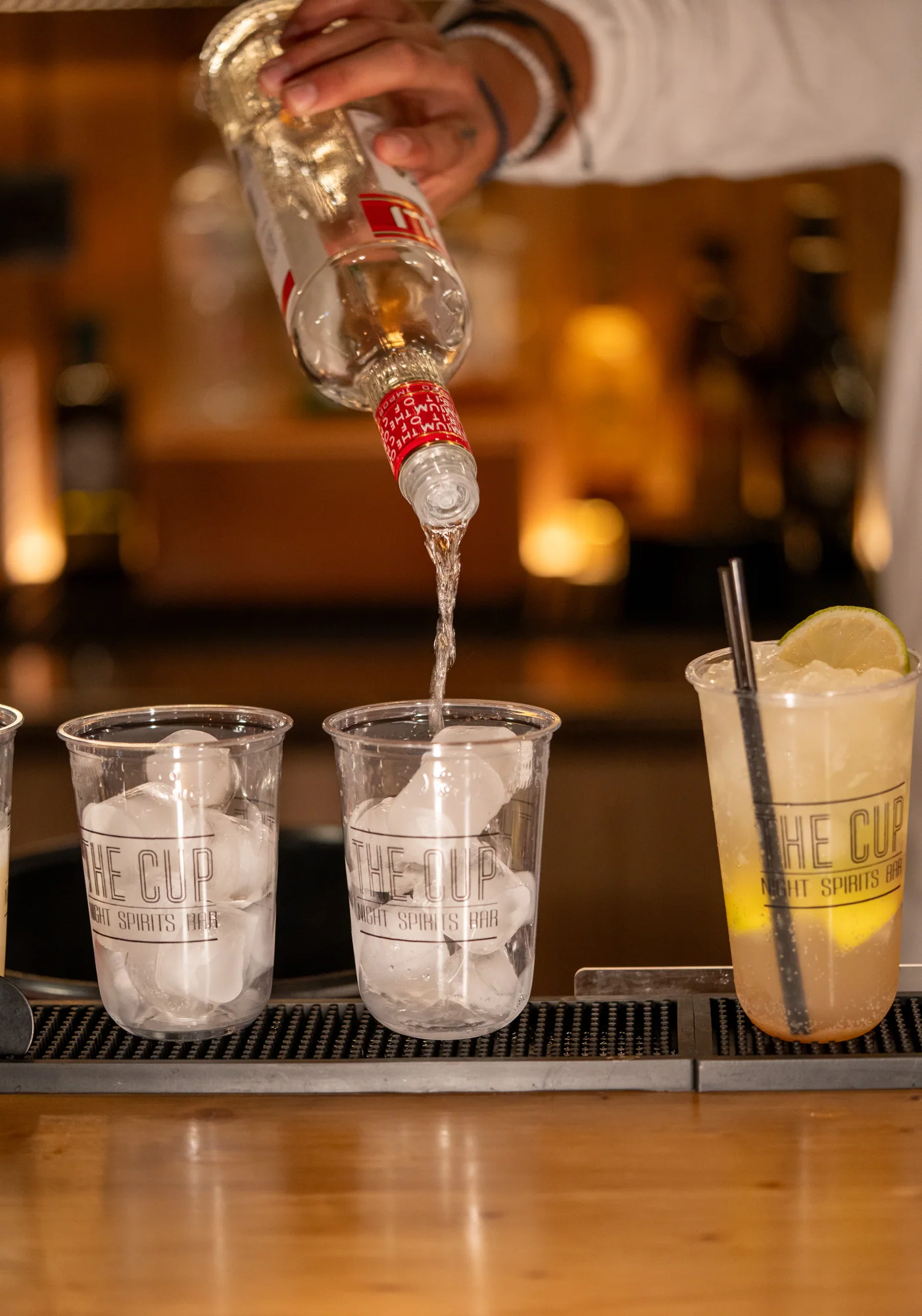 A bartender preparing iced drinks in The Cup branded cups