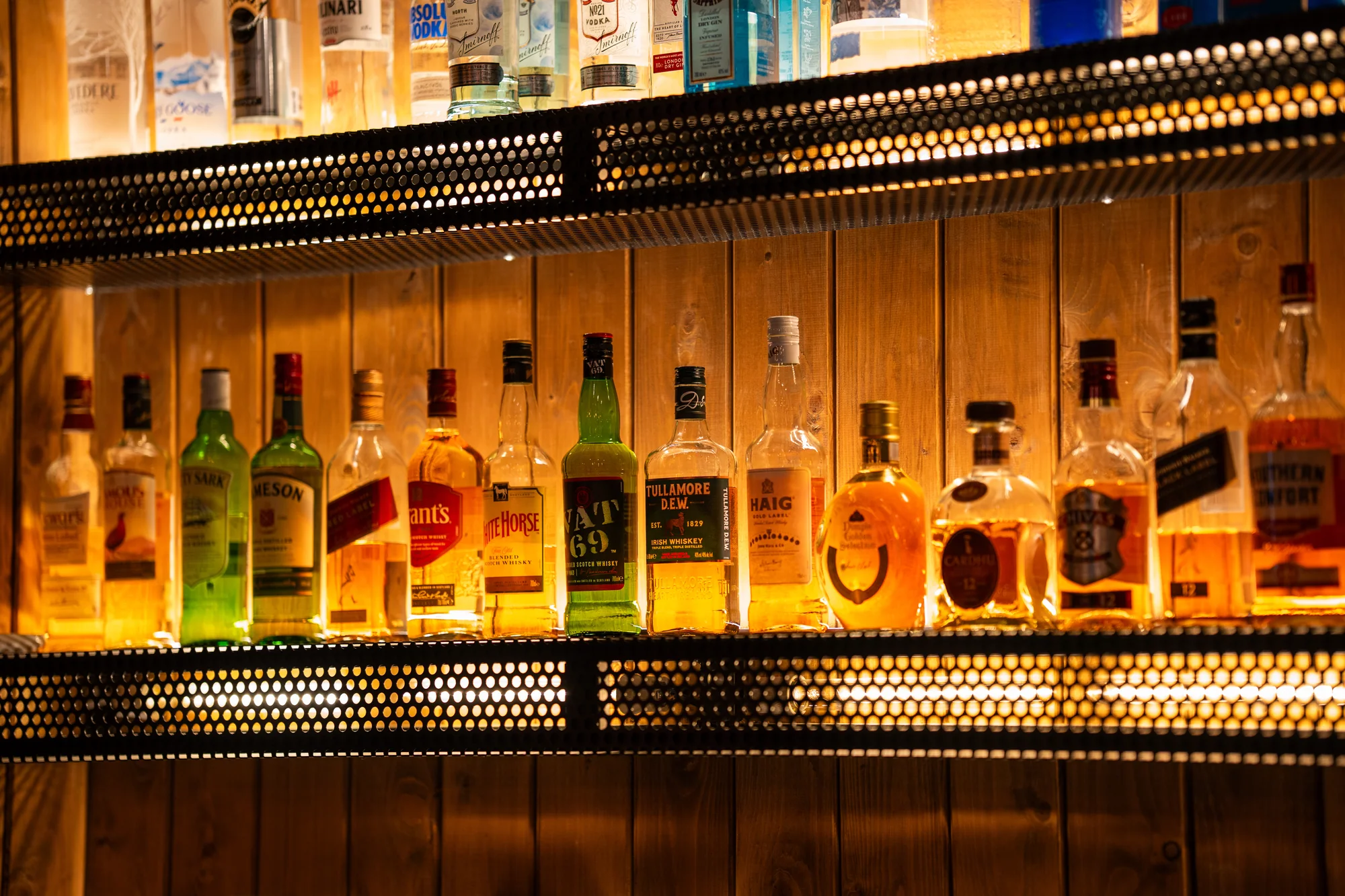 Whisky bottles on warmly lit shelves at The Cup